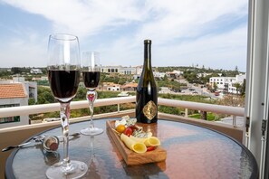A balcony with two wine glasses, a bottle, and a wooden board with cheese and fruit. - Stella Paradise by Checkin (Hersonissos)