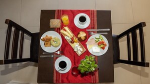 Un desayuno con dos platos de comida, dos tazas de café y una planta pequeña sobre un mantel rojo.