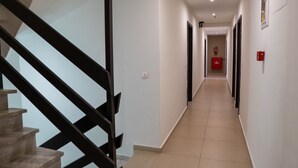 Un pasillo con una escalera a la izquierda que conduce a una habitación con un extintor rojo en la pared.