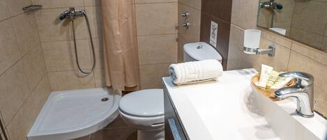 A bathroom with a bathtub, toilet, and a sink with a towel and toiletries.
