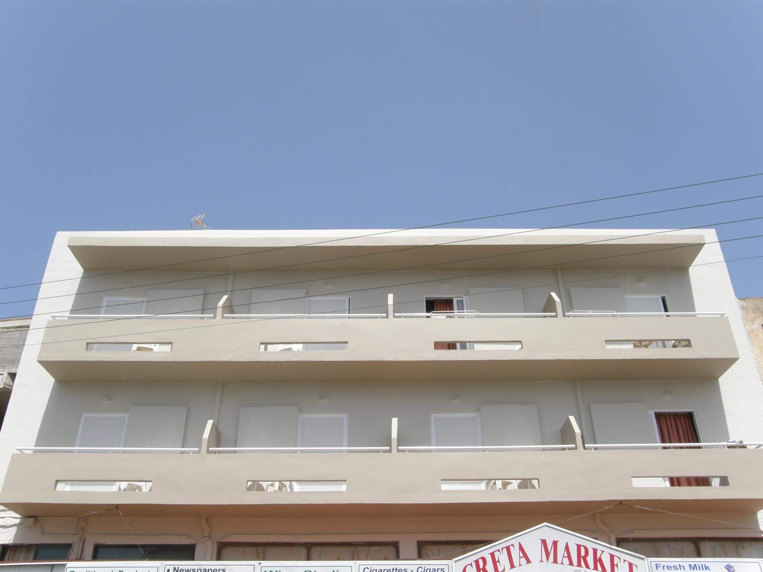 A multi-story building with a sign for 'CRETA MARKET' on the ground floor, indicating a market or store.