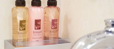 Three bottles of Juillet body care products on a white shelf.