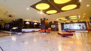A spacious lobby with a high ceiling, multiple seating areas, and a reception desk.