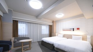 A hotel room with a large bed, a sofa, a small table, and a desk.