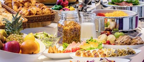 Un bufé con diversos alimentos, entre ellos frutas, ensaladas y productos de repostería.