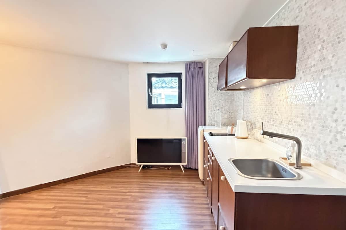 A compact kitchen with a built-in oven, a sink, and wooden flooring.