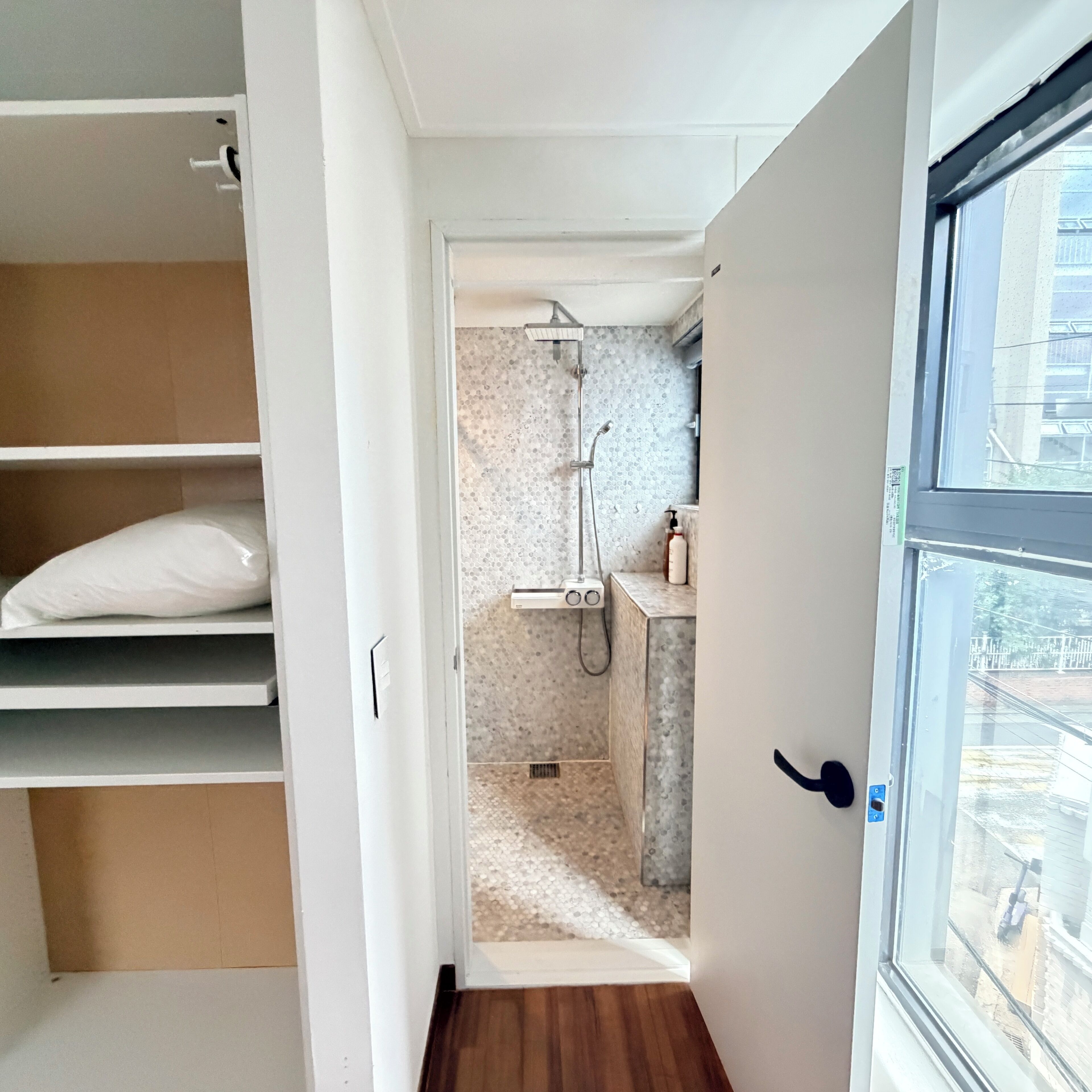 Een badkamer met een douche, toilet en wastafel. Er is een raam met uitzicht op buiten.