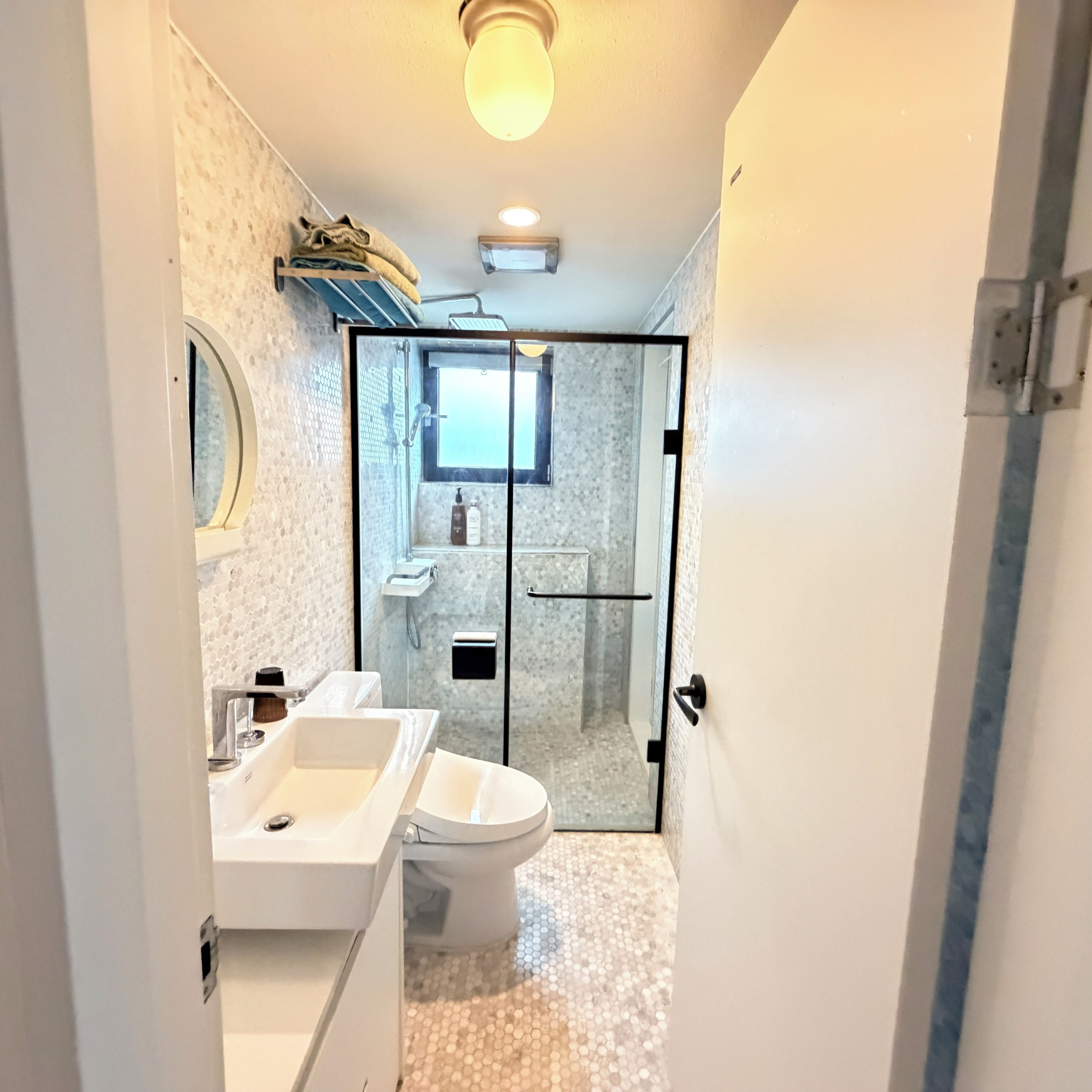 Ein modernes Badezimmer mit Duschkabine aus Glas, Toilette und Waschbecken.