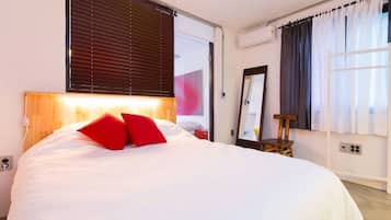 A bedroom with a large bed, a wooden headboard, a nightstand, a mirror, and a window with curtains.