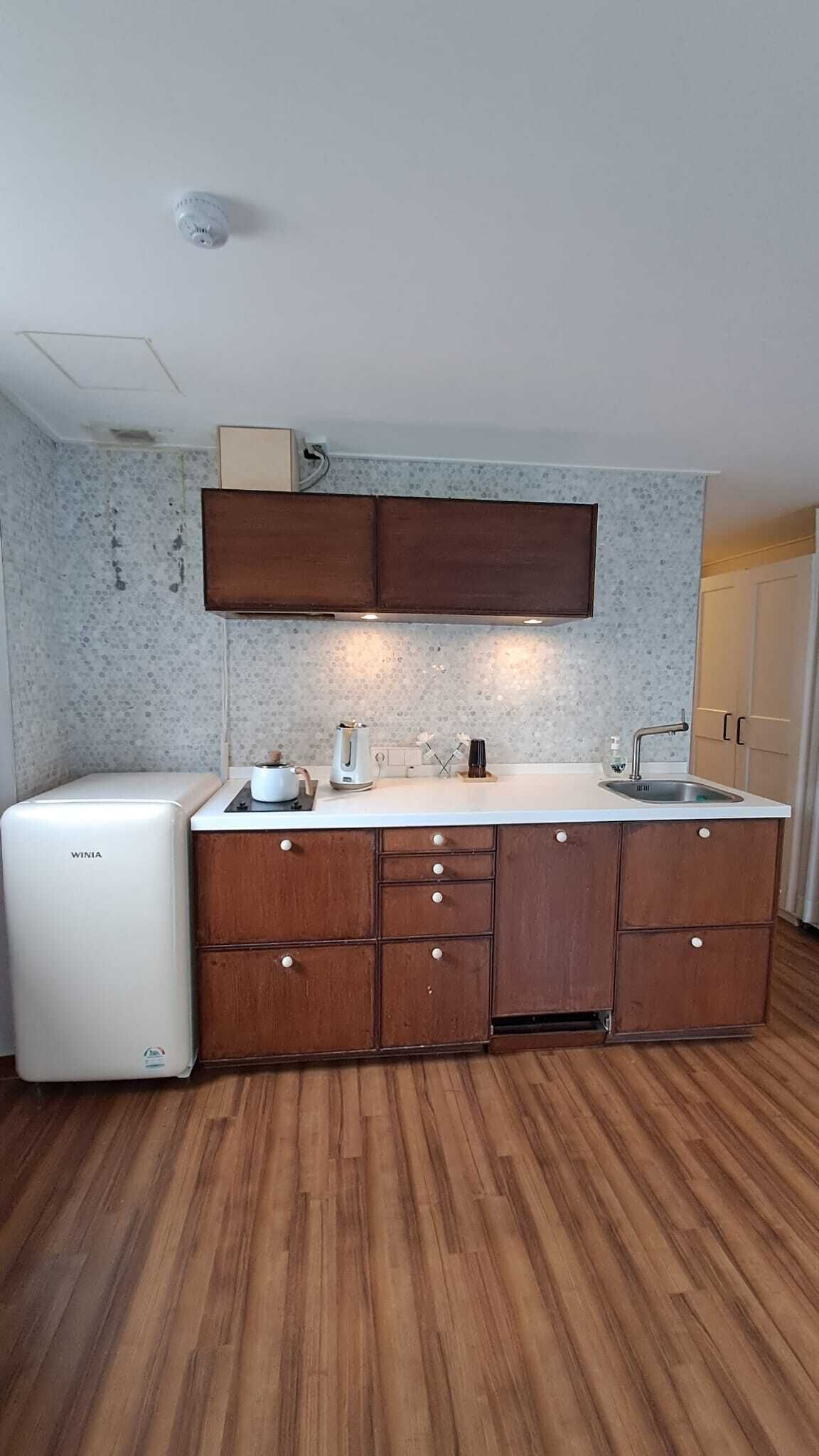 A compact kitchen with a built-in oven, a sink, and wooden cabinets.