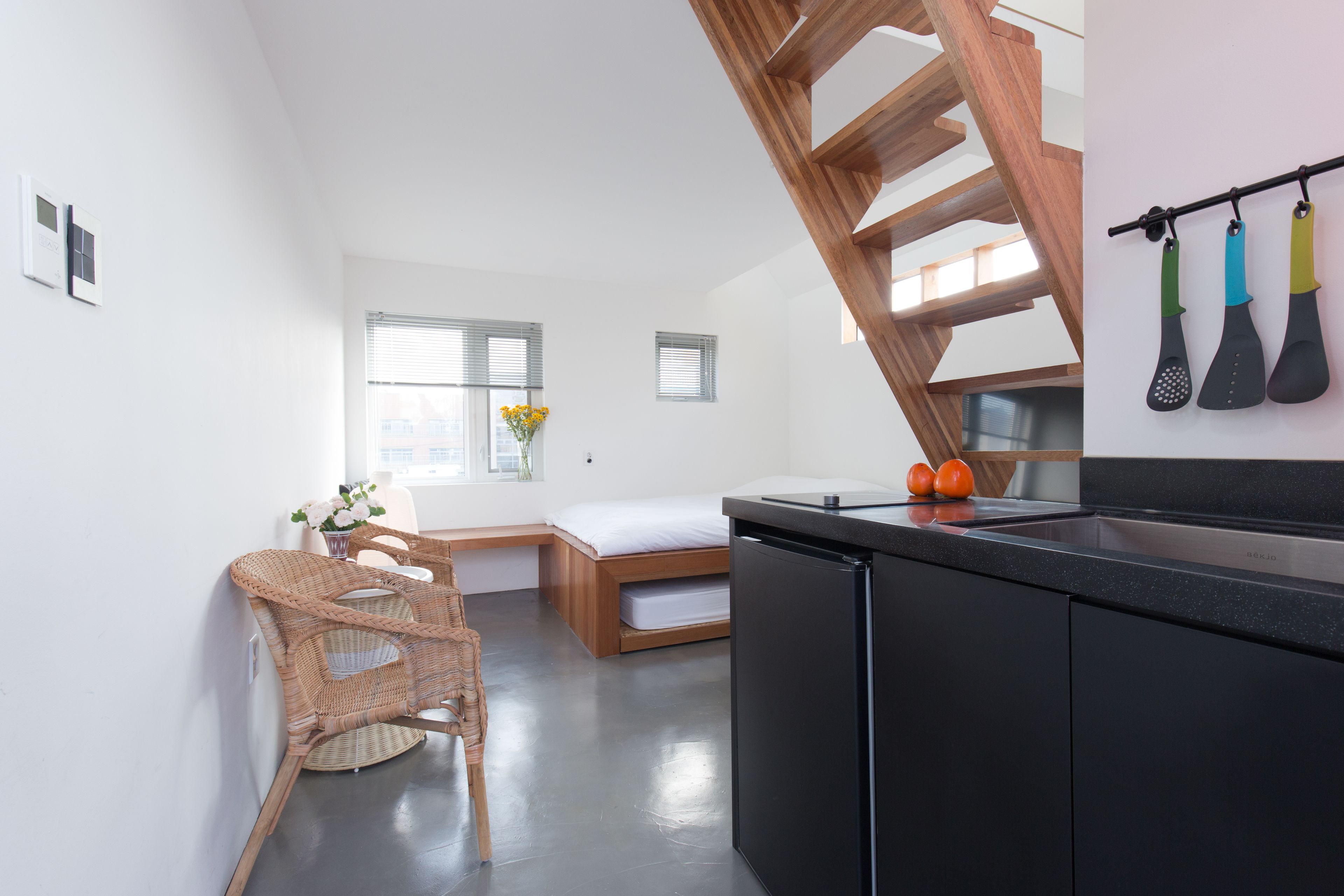 A modern kitchen with a black countertop, a wooden chair, a small dining table, and a built-in bench.