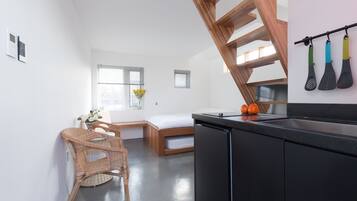 A modern kitchen with a black countertop, a wooden chair, a small dining table, and a built-in bench.