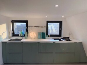 A modern kitchen with two windows, a built-in stove, and a large island with a sink. - iHouse ChinChin (Seoul)