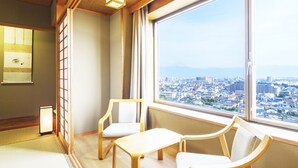 A room with a large window, two chairs, a small table, and a traditional Japanese sliding door.