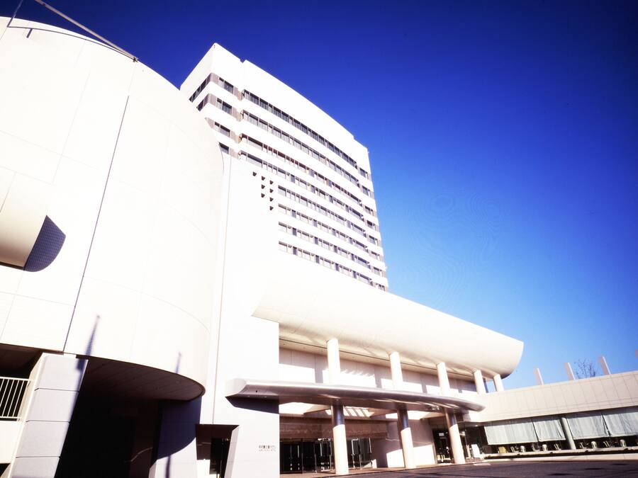 Un bâtiment moderne à la façade incurvée, doté de plusieurs étages et d’un hall d’entrée imposant agrémenté de colonnes.