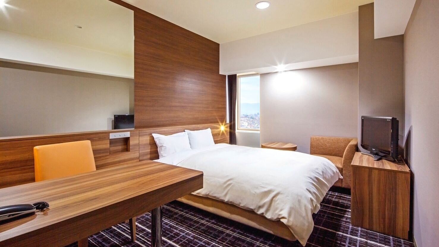 Une chambre d’hôtel équipée d’un lit, d’un bureau, d’une chaise, d’une télévision et d’une fenêtre donnant sur un paysage agréable.