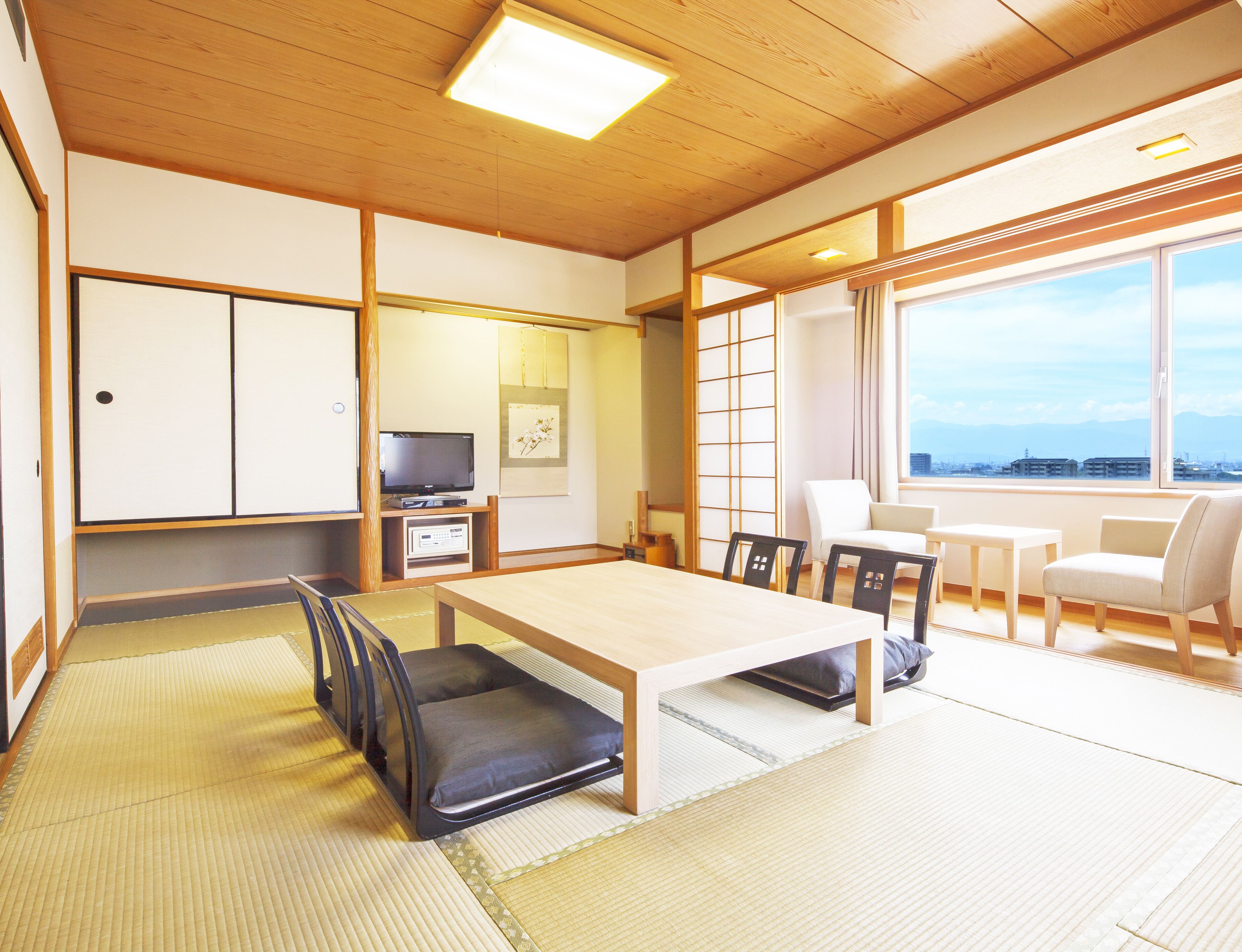A traditional Japanese room with tatami flooring, a low table, and a TV.