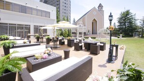 An outdoor patio area with wicker furniture, potted plants, and a gazebo.
