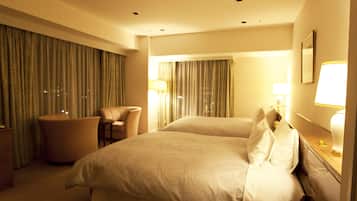 Una habitación de hotel con una cama grande, una silla, un escritorio con lámpara y cortinas en las ventanas.
