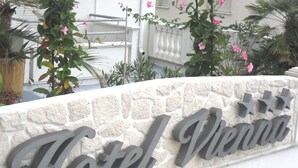 Een stenen muur met de tekst 'Hotel Vienna' in grote, vetgedrukte letters.