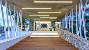 Un edificio moderno con terraza de madera, pared de piedra y paneles de vidrio.