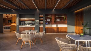 Un interior moderno con techo de madera, una zona de bar con estantes, sillas de mimbre y una mesa de comedor.