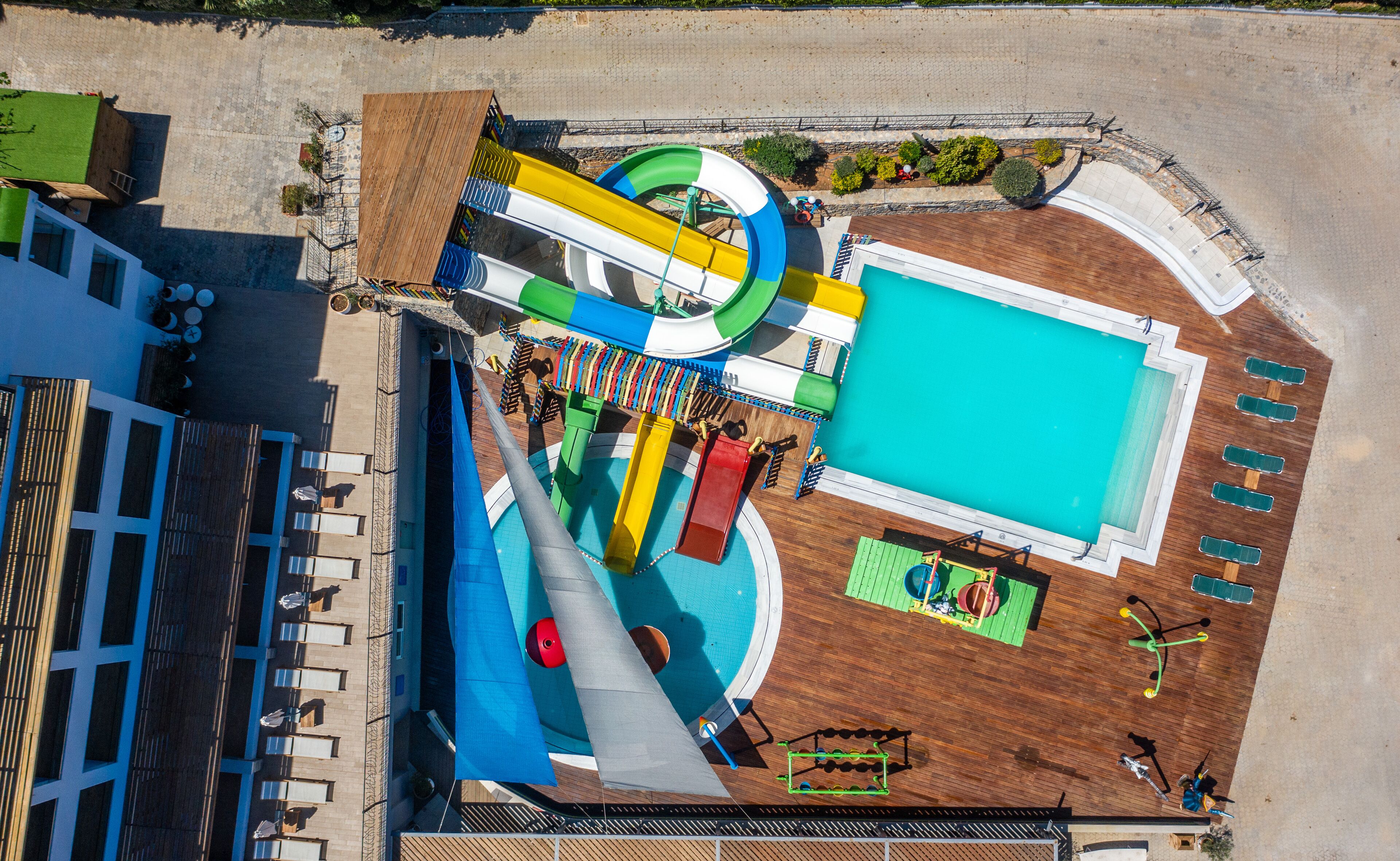 A pool area with a slide, a separate swimming pool, and sun loungers.