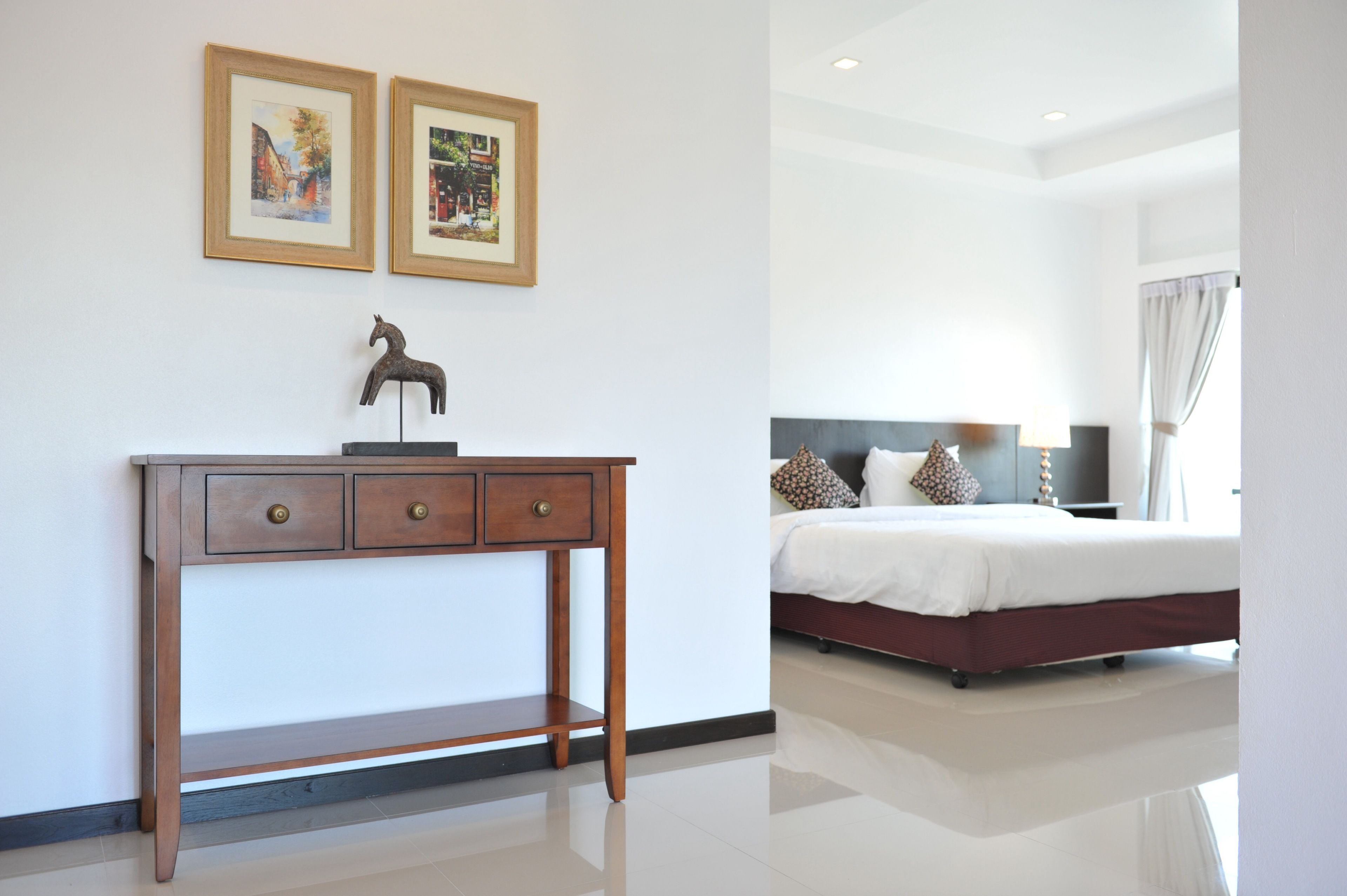 A bedroom with a bed, bedside table, and two framed pictures on the wall.