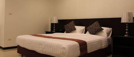 A neatly made bed with a white and brown bedspread, two decorative pillows, and two bedside lamps on either side.