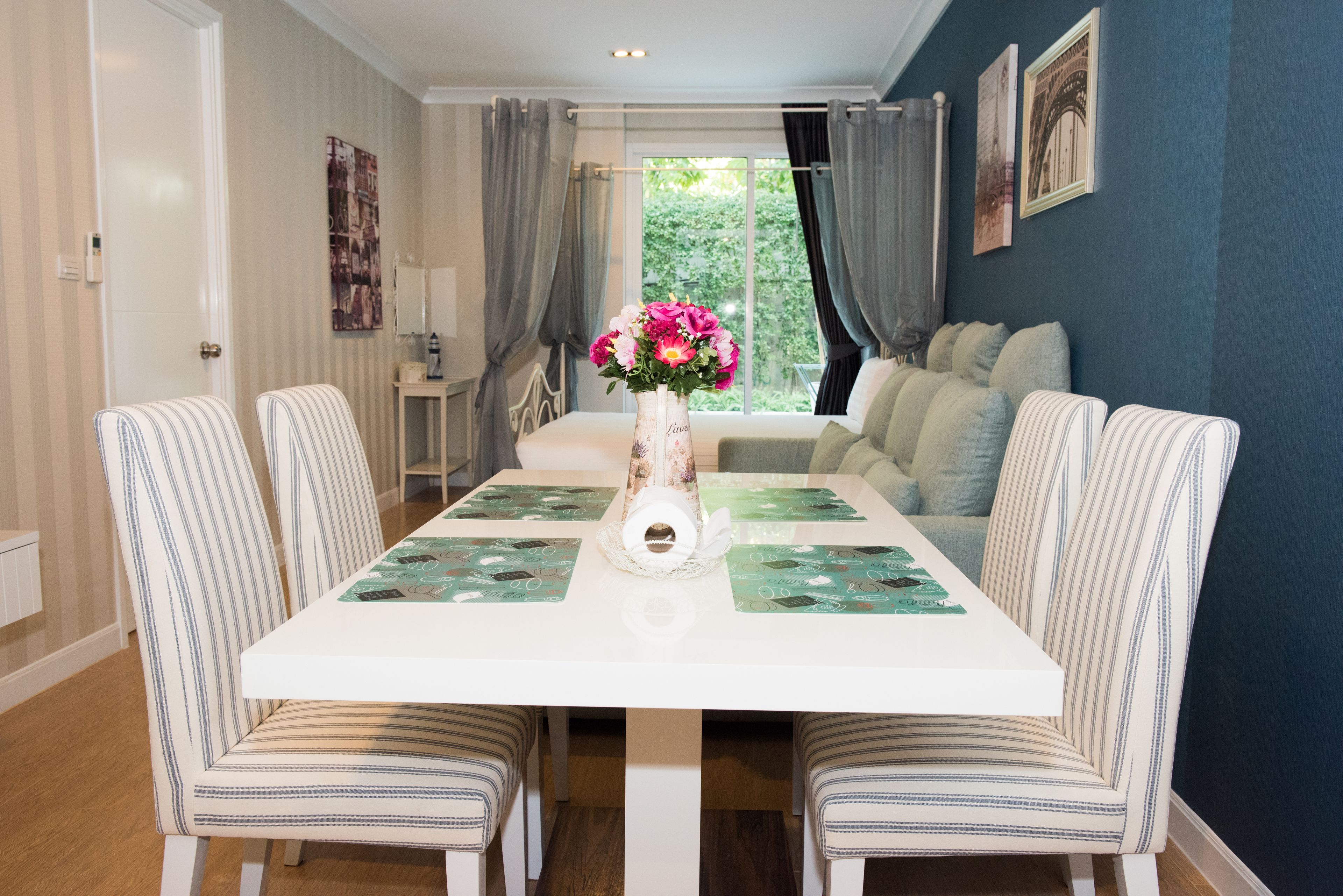 A dining area with a white table, striped chairs, and a vase with flowers.