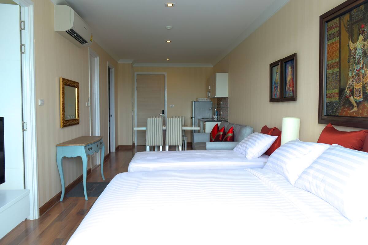 Une chambre d’hôtel avec deux lits, un bureau, une chaise, un réfrigérateur et un tableau au mur.