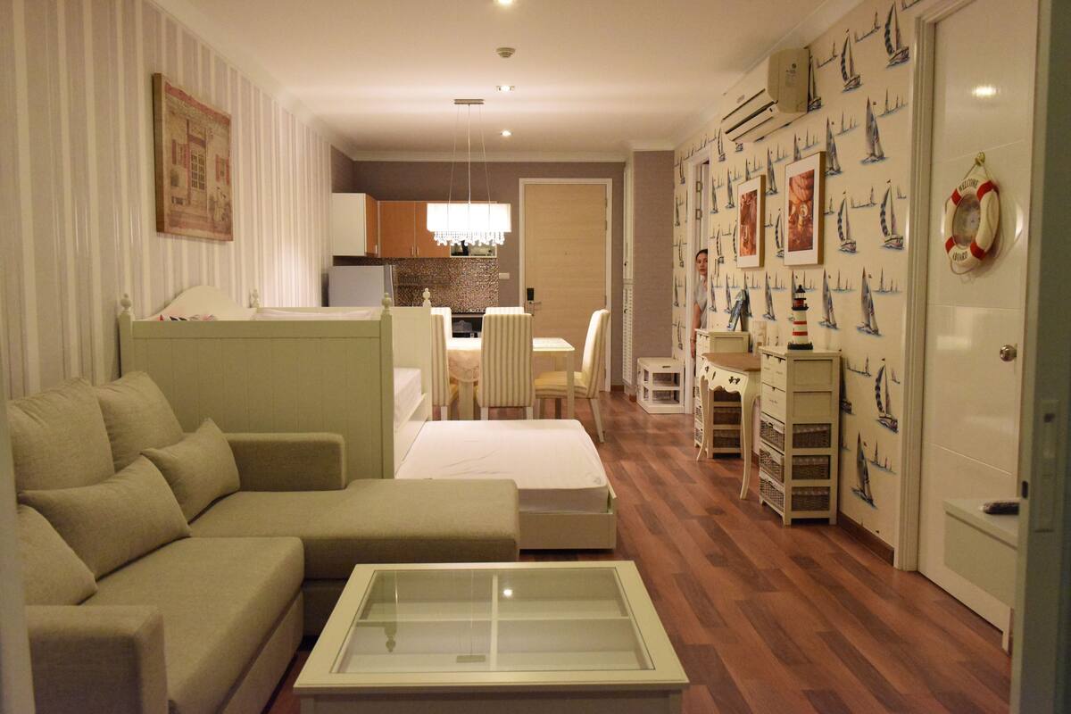 Un salon moderne comprenant un canapé, une table basse avec un plateau en verre et un coin repas avec une table et des chaises.