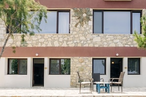 A two-story building with stone facade, multiple windows, and a patio with outdoor furniture. -  Villa Iliatoras (Malevizi)