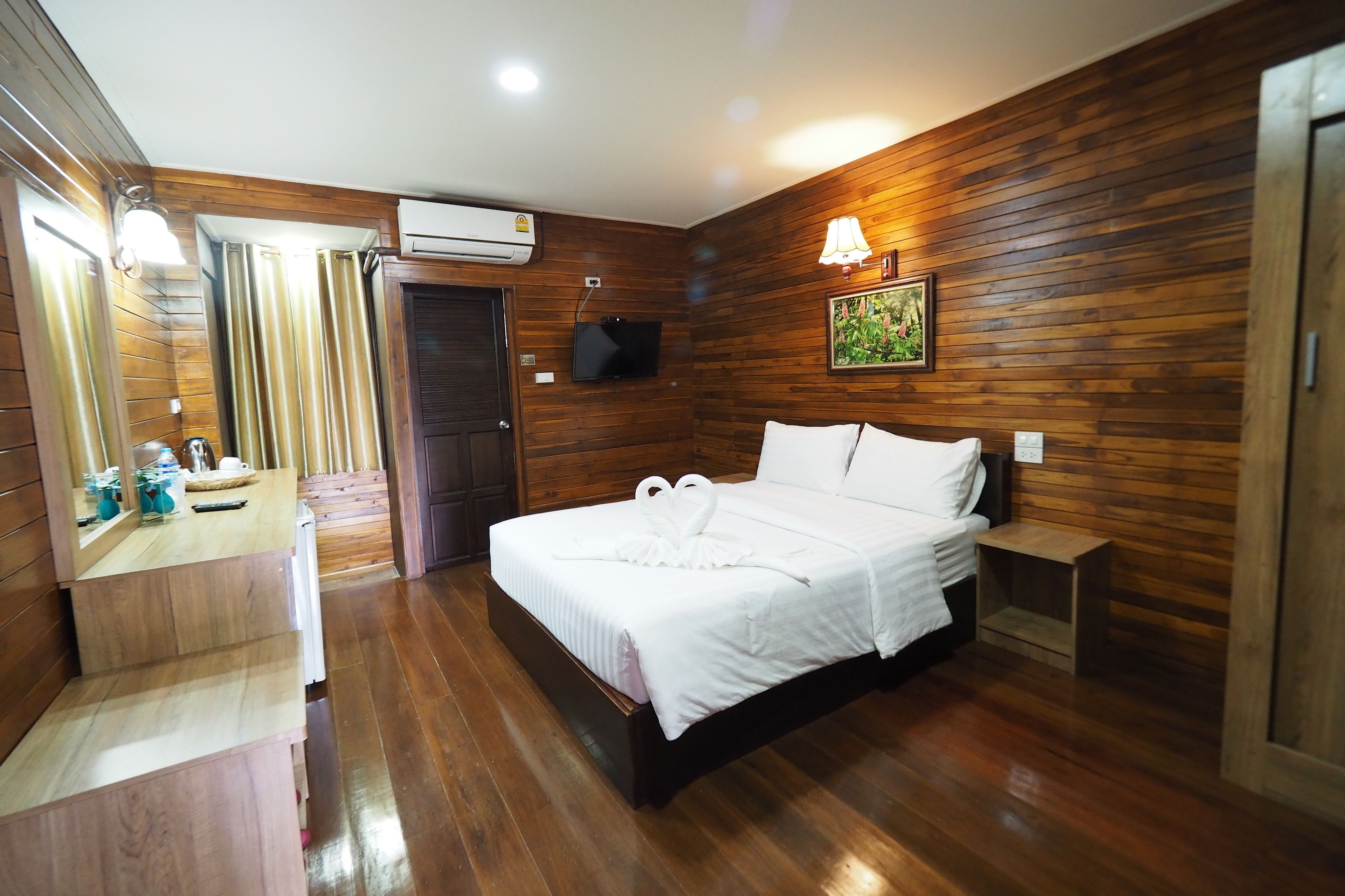 A wooden-paneled room with a bed, a TV, and a small table with toiletries.