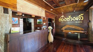Un área de recepción con paneles de madera, un mostrador de recepción, un letrero en la pared y un banco.