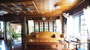 Una habitación amplia con techo de madera, un sofá grande y una mesa de comedor.