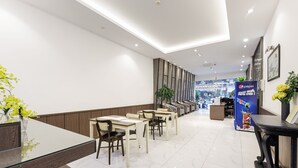 A modern hotel lobby with a long reception desk, seating area, and a Pepsi advertisement. - Collection O Le Grand Hanoi hotel – The Tryst (Hanoi)