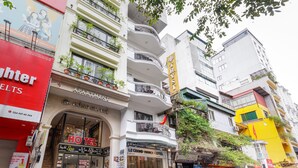 A multi-story hotel with a grand entrance, balconies with plants, and various signs including "HOTEL" and "LE GRAND HANHUI HOTEL". - Collection O Le Grand Hanoi hotel – The Tryst (Hanoi)