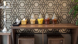 A wooden counter with jars of pasta and condiments, a candle, and a decorative metal candelabra. - Collection O Le Grand Hanoi hotel – The Tryst (Hanoi)