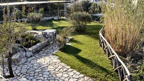 A stone pathway leading through a well-maintained garden with a grassy area and various shrubs. - Casa Colarusso (Massa Lubrense)