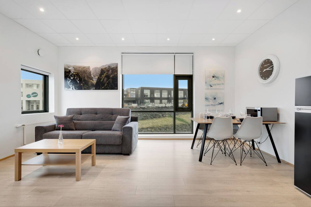 A modern living room with a sofa, a coffee table, and a dining area with chairs and a table.