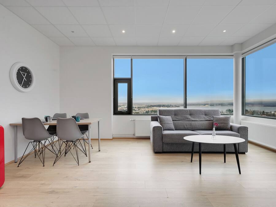 Una habitación moderna con zona de comedor, sofá y ventana grande con vistas a la ciudad.