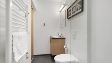 Et moderne badeværelse med toilet, håndvask og håndklædetørrer.