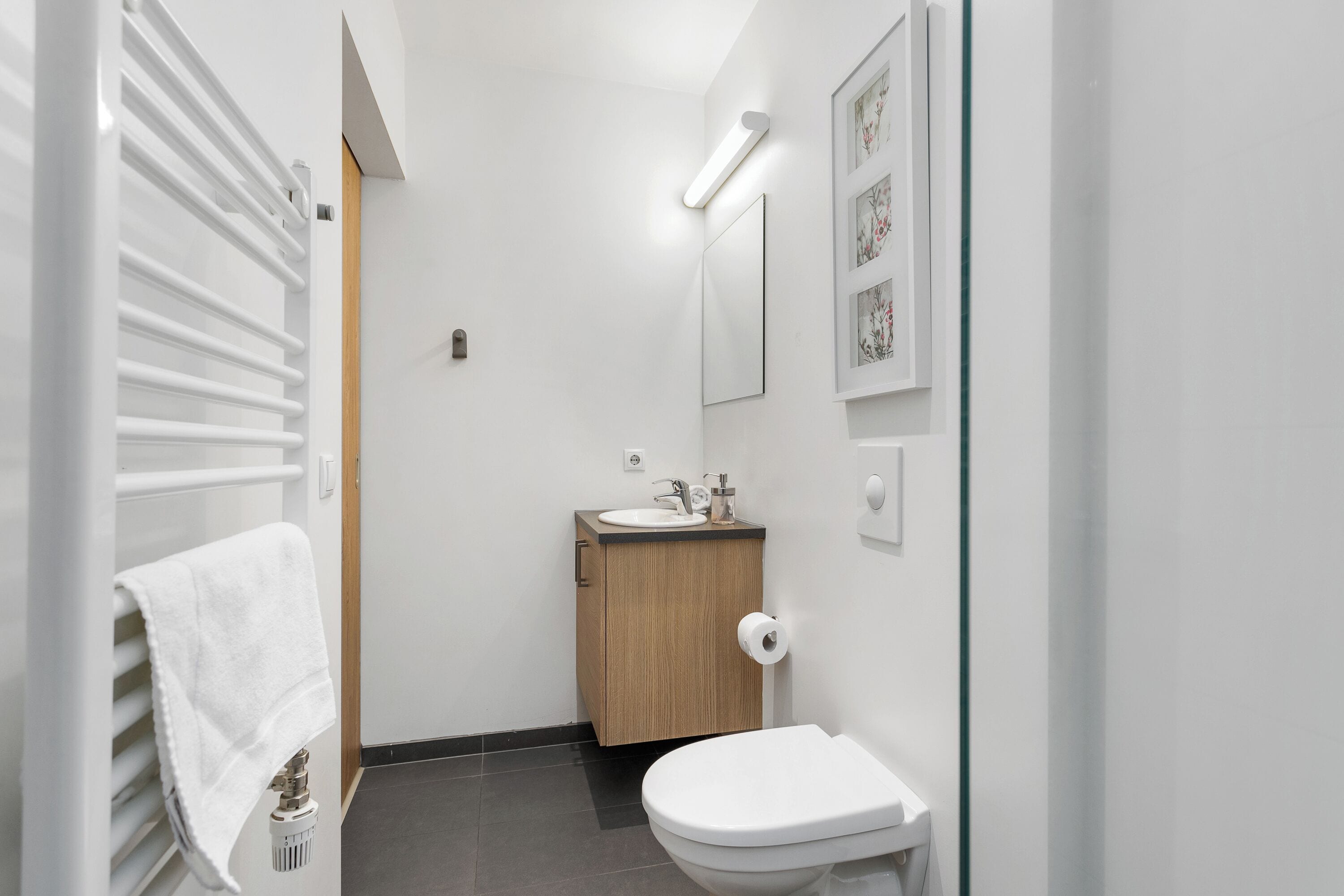A modern bathroom with a toilet, sink, and towel rack.