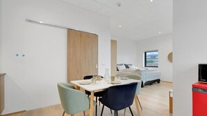 Une chambre moderne équipée d’une table à manger, de chaises, d’un lit et d’un téléviseur.