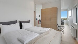 Une chambre d’hôtel moderne avec un grand lit, une armoire en bois et une vue sur la ville.