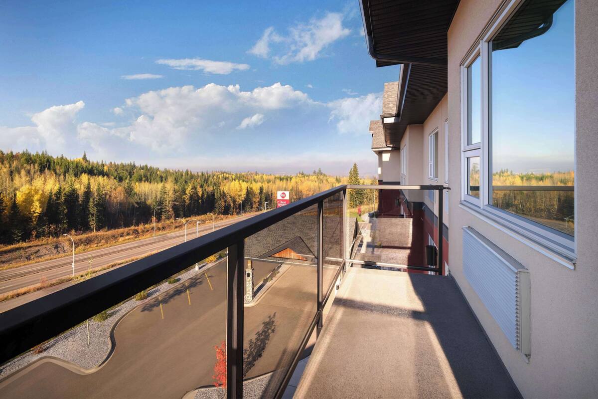 Ein Balkon mit Blick auf eine Straße und einen Wald.