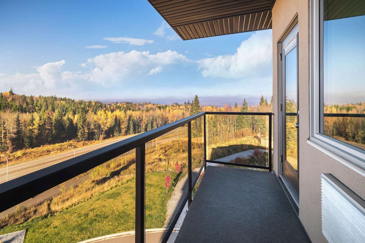 Ein Balkon mit Blick auf einen Wald und eine Straße.