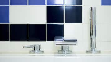 A bathroom with a chrome faucet, a mirror, and a vertical showerhead.