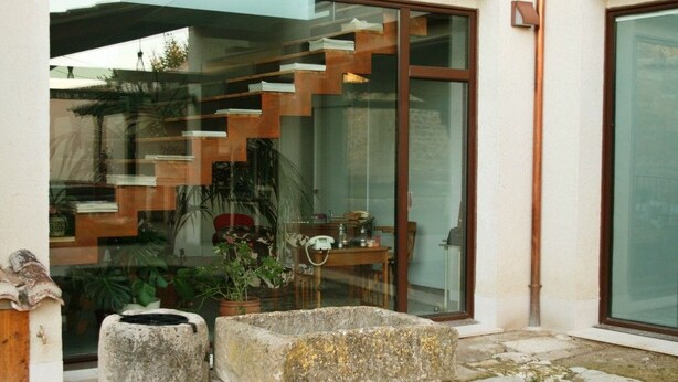 Un banco de piedra y una escalera que lleva a una puerta de cristal.
